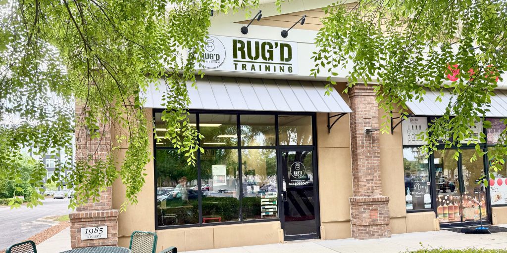 Exterior sign for RUG'D Training gym surrounded by greenery, representing the Mount Pleasant facility where NJB Training clients work out.